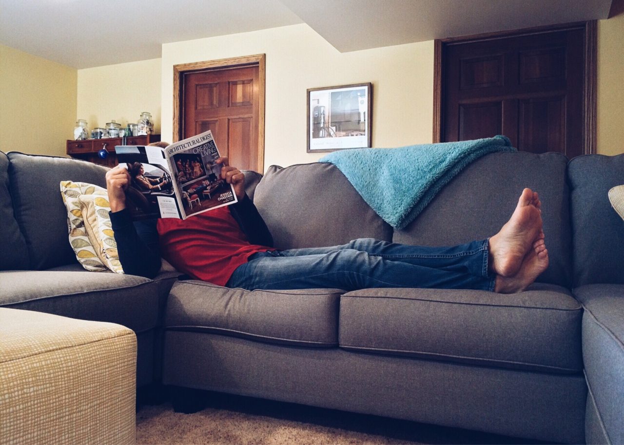 Man sitting on couch reading architectural magazine.